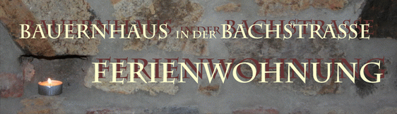 Header der Website mit Schrift vor Bruchsteinwand und Teelicht